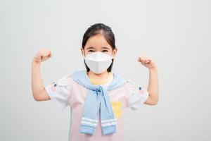 menina asiática usando máscara respiratória para proteger o surto de coronavírus e apontando a mão para um fundo em branco, novo vírus covid-19 foto