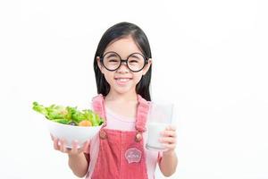 crianças menina ásia comendo legumes e leite foto