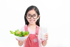 crianças menina ásia comendo legumes e leite foto