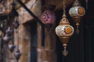 lâmpadas e lanternas turcas coloridas tradicionais feitas à mão, foco seletivo na lanterna, fundo desfocado, lanternas de souvenirs populares penduradas na loja para venda. foto
