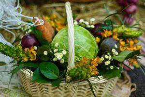 cesta com vegetais orgânicos na grama verde e flores. ao ar livre. vegetais recém-colhidos. vegetais crus em cesta de vime cesta com legumes e flores foto