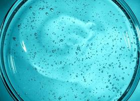 gel com ácido hialurônico. fundo azul com bolhas de oxigênio. gel cosmético em uma placa de petri foto