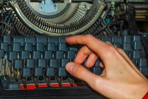 a mão de uma mulher escreve em uma velha máquina de escrever. foto