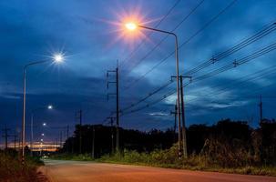 uma bela paisagem à luz das estrelas de lanternas laranja e brancas ao lado de uma estrada rural. foto