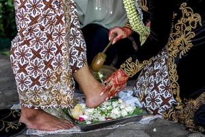 tradição de casamento na indonésia a noiva lava os pés do noivo foto