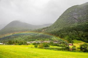 arco-íris colorido sobre os campos, lago e casas da vila de skei, noruega. foto