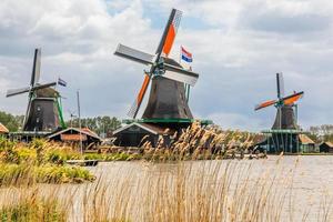 moinhos de vento holandeses coloridos no rio zaan, zaanse schans, zaandam, países baixos foto