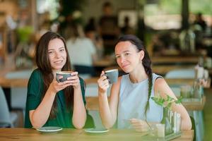 mulheres jovens sorridentes felizes com xícaras de café no café. conceito de comunicação e amizade