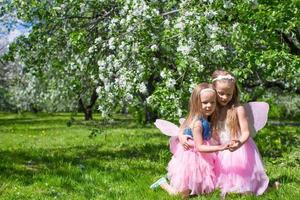 meninas adoráveis com asas de borboleta sob a macieira em flor foto