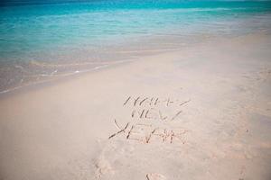 feliz ano novo escrito na areia branca foto