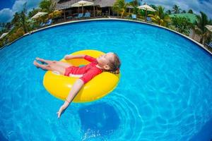menina com círculo de borracha inflável se divertindo na piscina foto