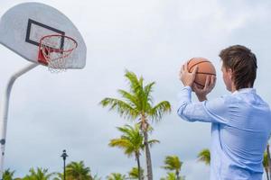 jovem jogando basquete lá fora no resort exótico foto