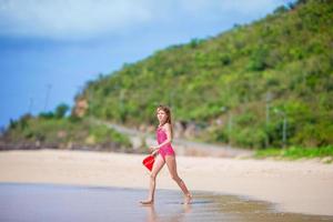 adorável menina brincando com brinquedos de praia na praia tropical branca foto