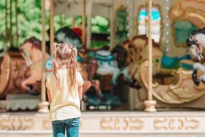 adorável menina perto do carrossel ao ar livre foto