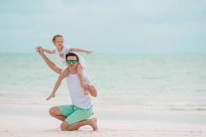 feliz pai e sua adorável filha na praia tropical se divertindo foto