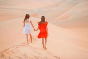 meninas entre dunas no deserto de rub al-khali nos Emirados Árabes Unidos foto