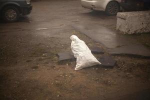 saco com conteúdo desconhecido na rua. saco branco fica no chão. foto