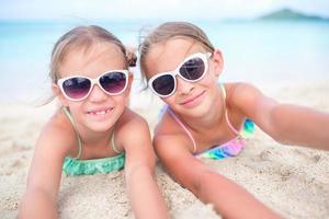 feche as meninas na praia. crianças felizes deitado na praia de areia branca quente foto