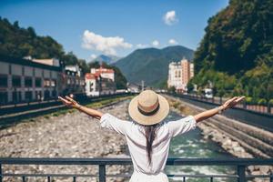 garota feliz no chapéu na margem de um rio de montanha em uma cidade europeia. foto