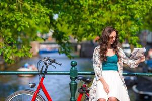 mulher jovem feliz com mapa da cidade e bicicletas na cidade europeia foto