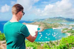 jovem turista com mapa de fundo do porto inglês de shirley heights, antígua, baía paradisíaca na ilha tropical no mar do caribe foto