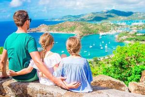 adoráveis crianças e jovem pai apreciando a vista do pitoresco porto inglês em antígua, no mar do caribe foto