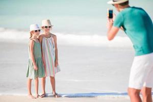 homem tirando uma foto de seus filhos na praia