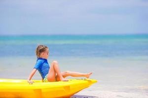 adorável garotinha andando de caiaque nas férias na praia foto