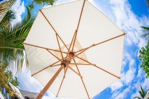 guarda-chuva branco fundo céu azul na praia branca tropical foto