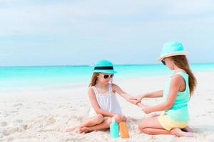 crianças aplicando protetor solar umas nas outras na praia. o conceito de proteção contra radiação ultravioleta foto