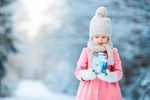 menina adorável com lanterna na floresta congelada no natal no dia de inverno foto