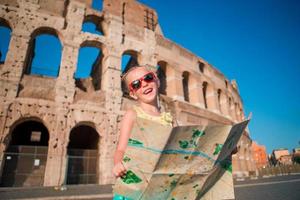 adorável menina ativa com mapa na frente do Coliseu, em Roma, Itália. garoto passando a infância na europa foto