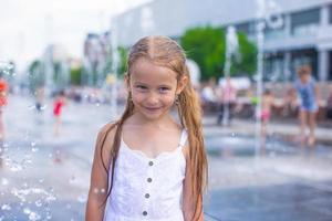 menina se divertir na fonte ao ar livre em dia quente foto