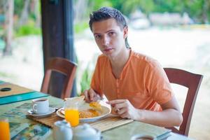 jovem tomando café da manhã no restaurante do resort foto