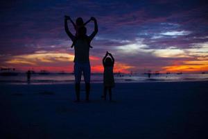 silhueta de pai e filhas por do sol na praia de boracay foto