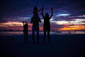 família de quatro pessoas silhueta por do sol na praia em boracay foto