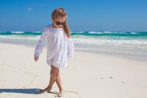 menina adorável em roupas bonitas dançando na praia tropical foto