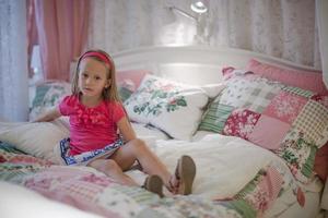 menina sentada em uma grande cama colorida foto