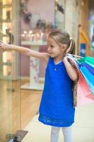 menina bonita com pacotes em um grande centro comercial foto