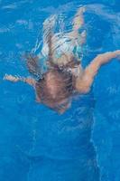 menina bonita e feliz nadando na piscina foto
