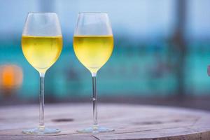 dois copos de saboroso vinho branco ao pôr do sol na mesa de madeira foto