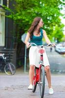 jovem mulher feliz em bicicleta na cidade europeia foto