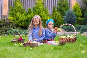 duas meninas felizes com grande colheita de outono de tomates foto