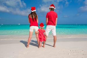 família feliz em chapéus de Papai Noel se divertindo durante as férias no Caribe foto