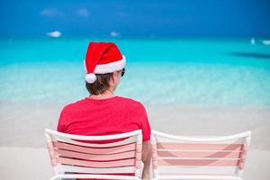 homem de chapéu de papai noel aproveite as férias de verão na praia tropical foto