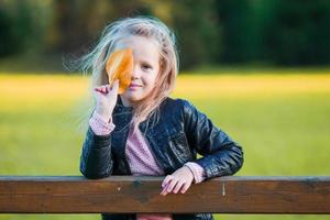 menina incrível ao ar livre em lindo dia quente no parque outono com folha amarela no outono foto