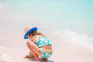 menina na praia branca tropical fazendo castelo de areia foto