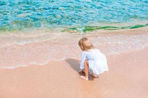 adorável menina se divertir na praia tropical durante as férias foto