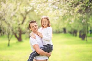 família de pai e filha no jardim de cereja florescendo foto