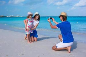 jovem pai fazendo foto no telefone da família na praia